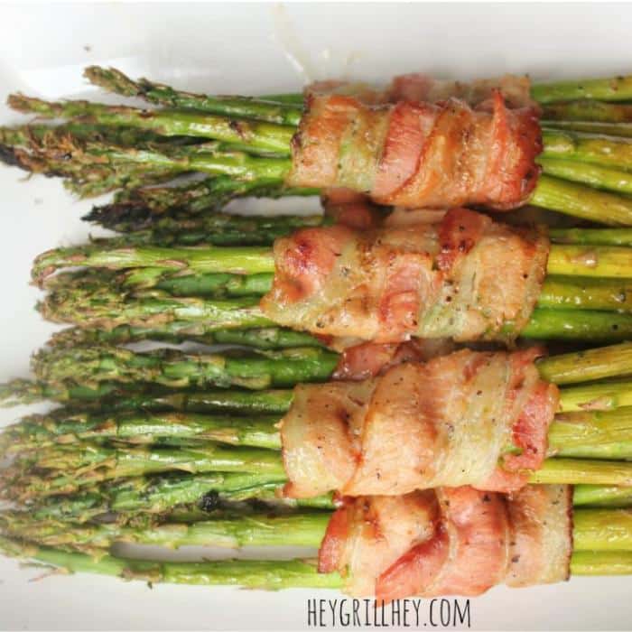 row of bacon wrapped asparagus on a white platter