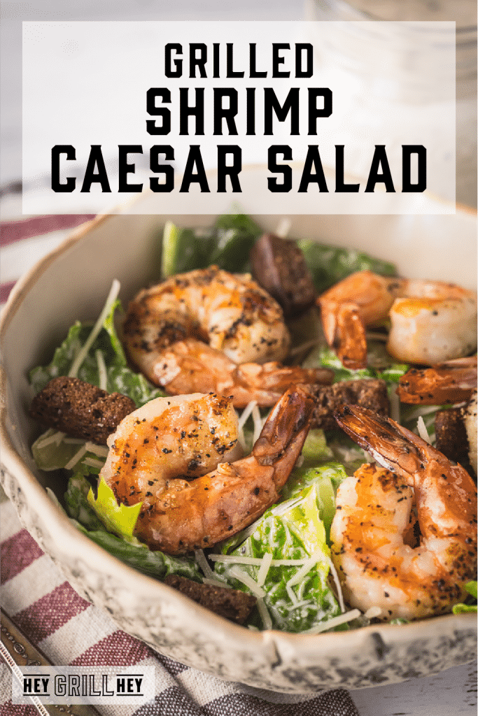 Lemon pepper grilled shrimp on top of a bed of lettuce with text overlay - Grilled Shrimp Caesar Salad.