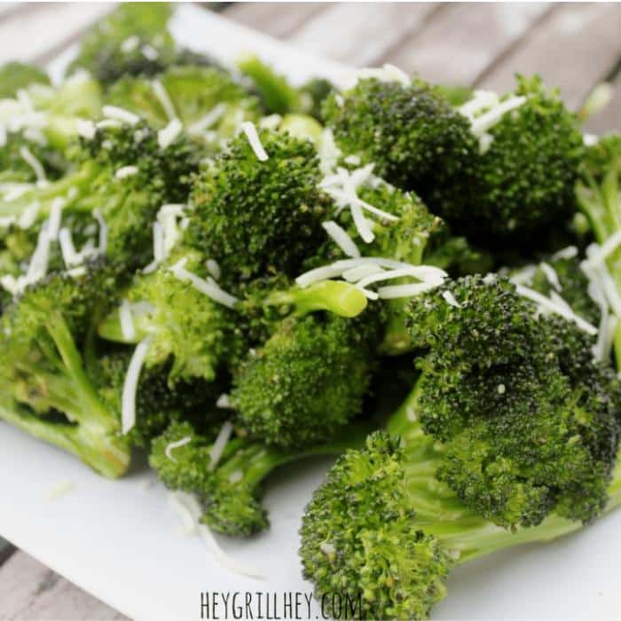 grilled broccoli on a plate topped with shredded cheese