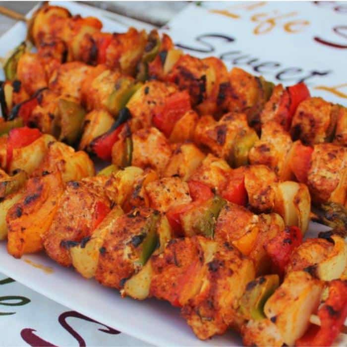 grilled buffalo chicken skewers stacked on a while platter
