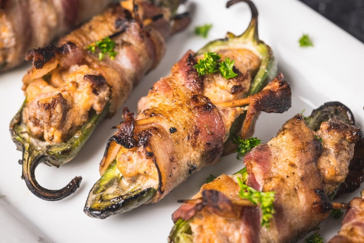 Grilled stuffed jalapenos lined up on a serving platter.