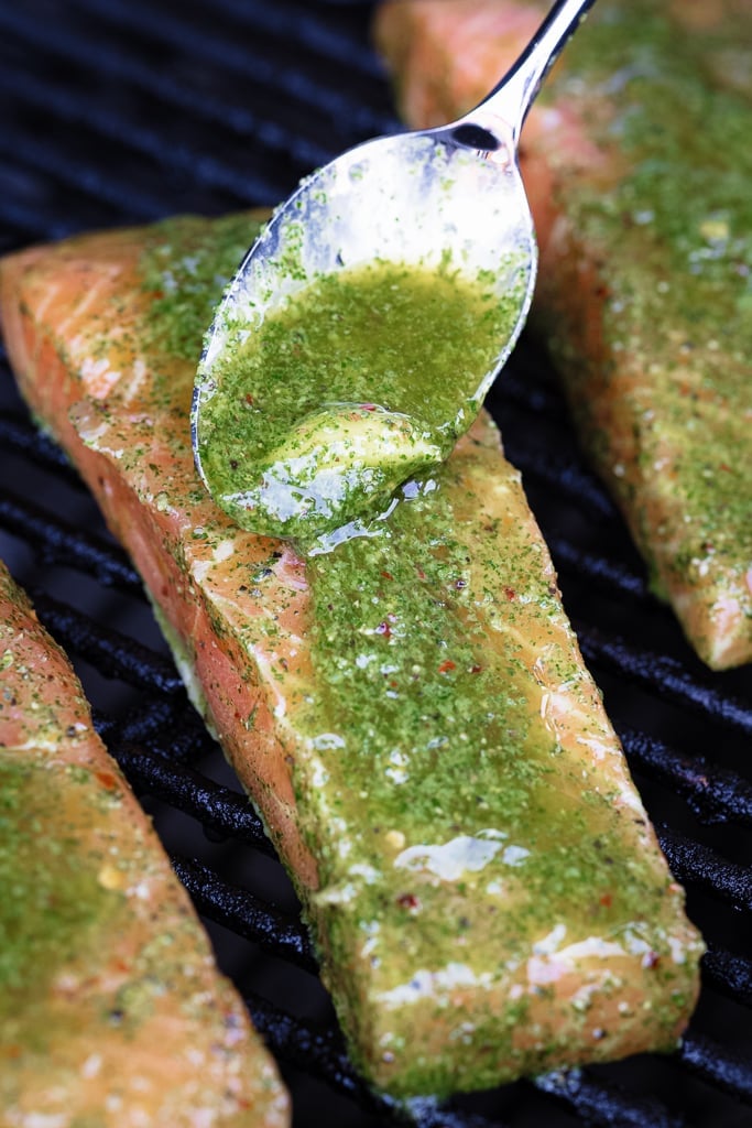Cilantro lime marinade being spooned onto a salmon fillet on the grill.