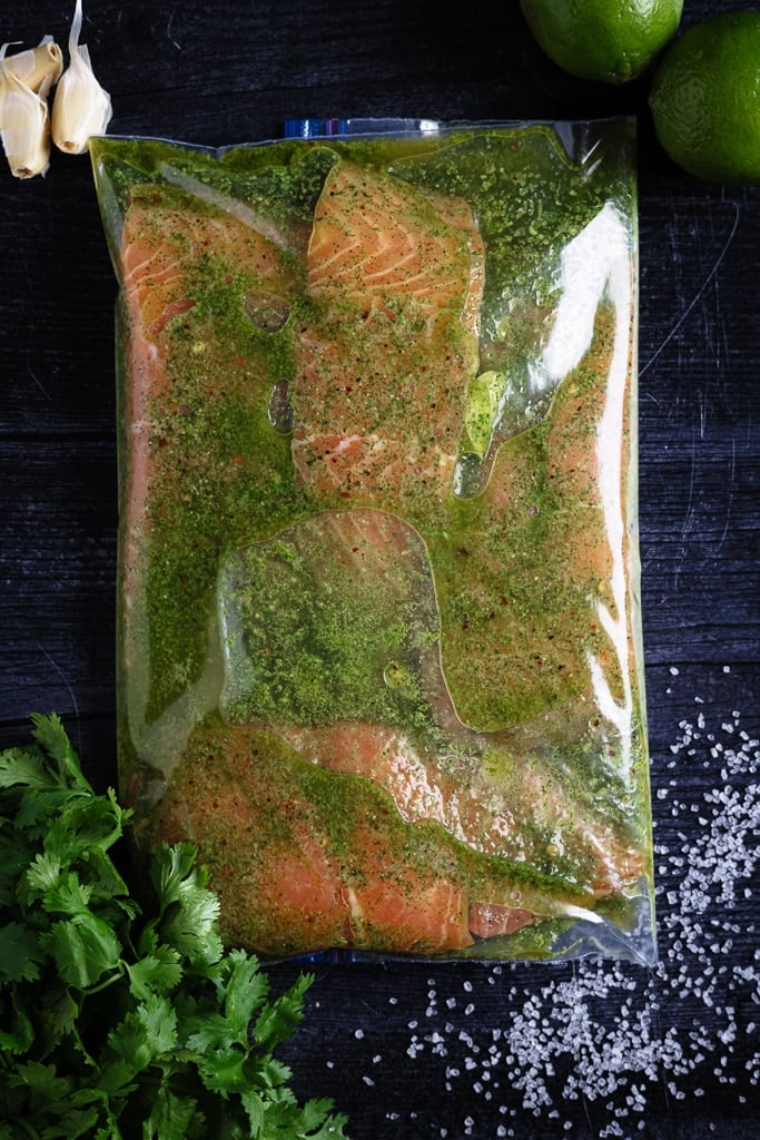 Three salmon fillets in a zip-top bag with cilantro lime marinade.