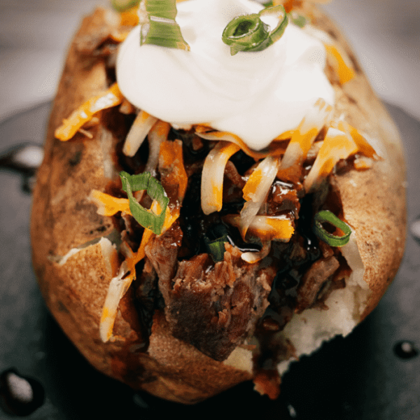 Brisket stuffed baked potato topped with shredded cheese and sour cream.