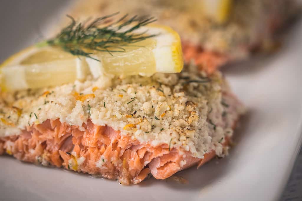Parmesan crusted salmon garnished with lemon slices and dill.