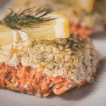 Parmesan crusted salmon garnished with lemon slices and dill.