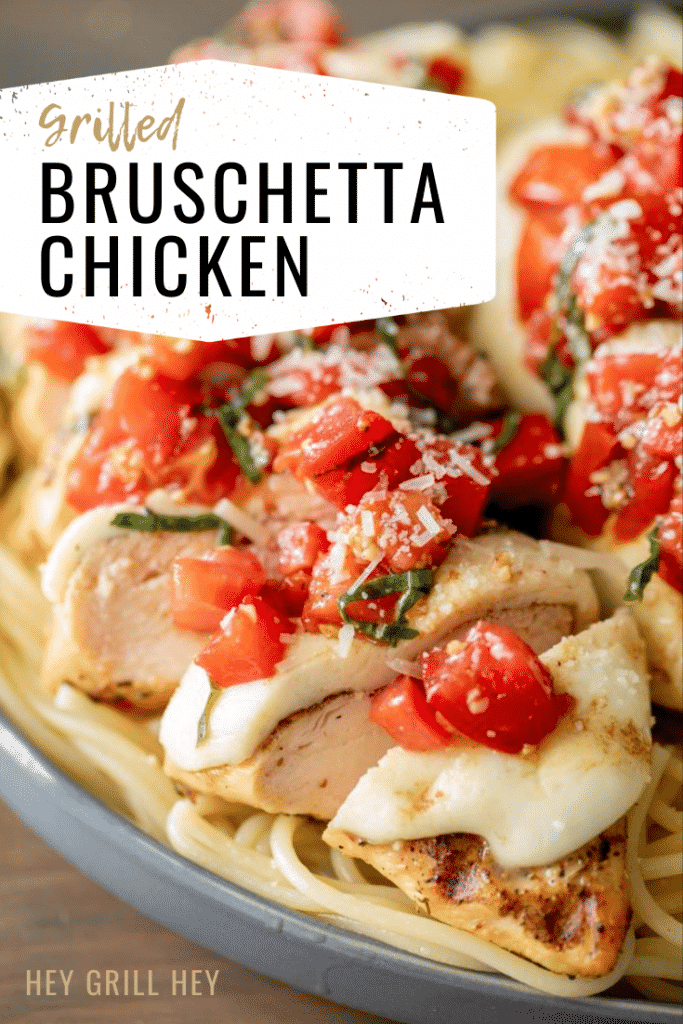 Sliced grilled chicken topped with melty mozzarella and chopped tomatoes and basil, laid on top of cooked spaghetti noodles. Text Overlay: Grilled Bruschetta Chicken.