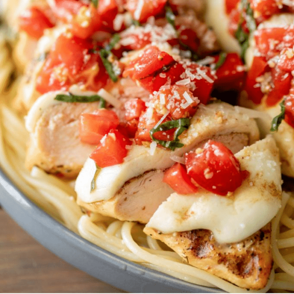 Grilled bruschetta chicken on top of cooked spaghetti noodles.