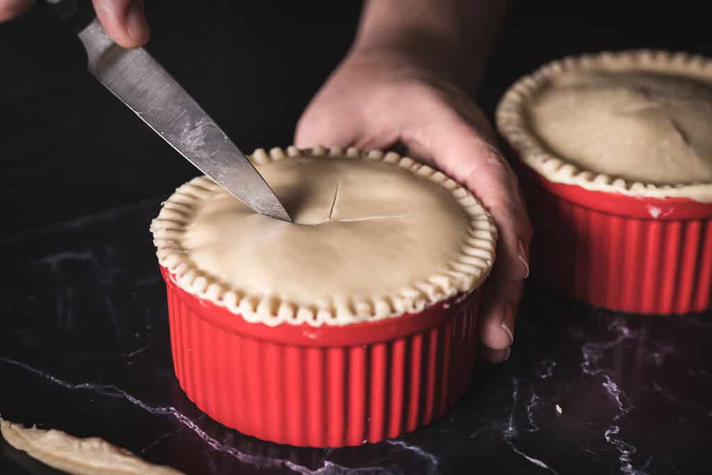 Knife scoring the top crust of a Guinness and steak pot pie