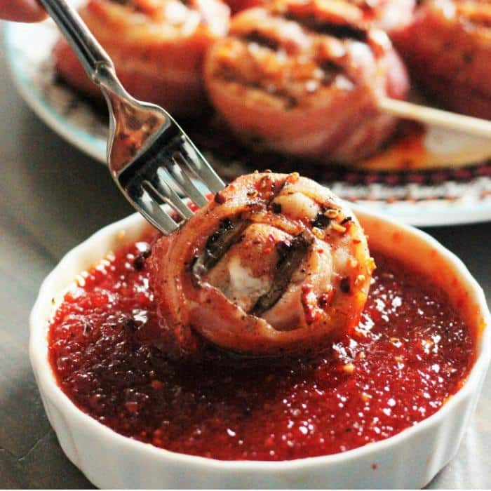 sweet and spicy chicken bacon lollipop on a fork being dipped in jalapeno jelly