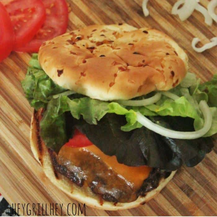 burger on a bun with lettuce, cheese, onion