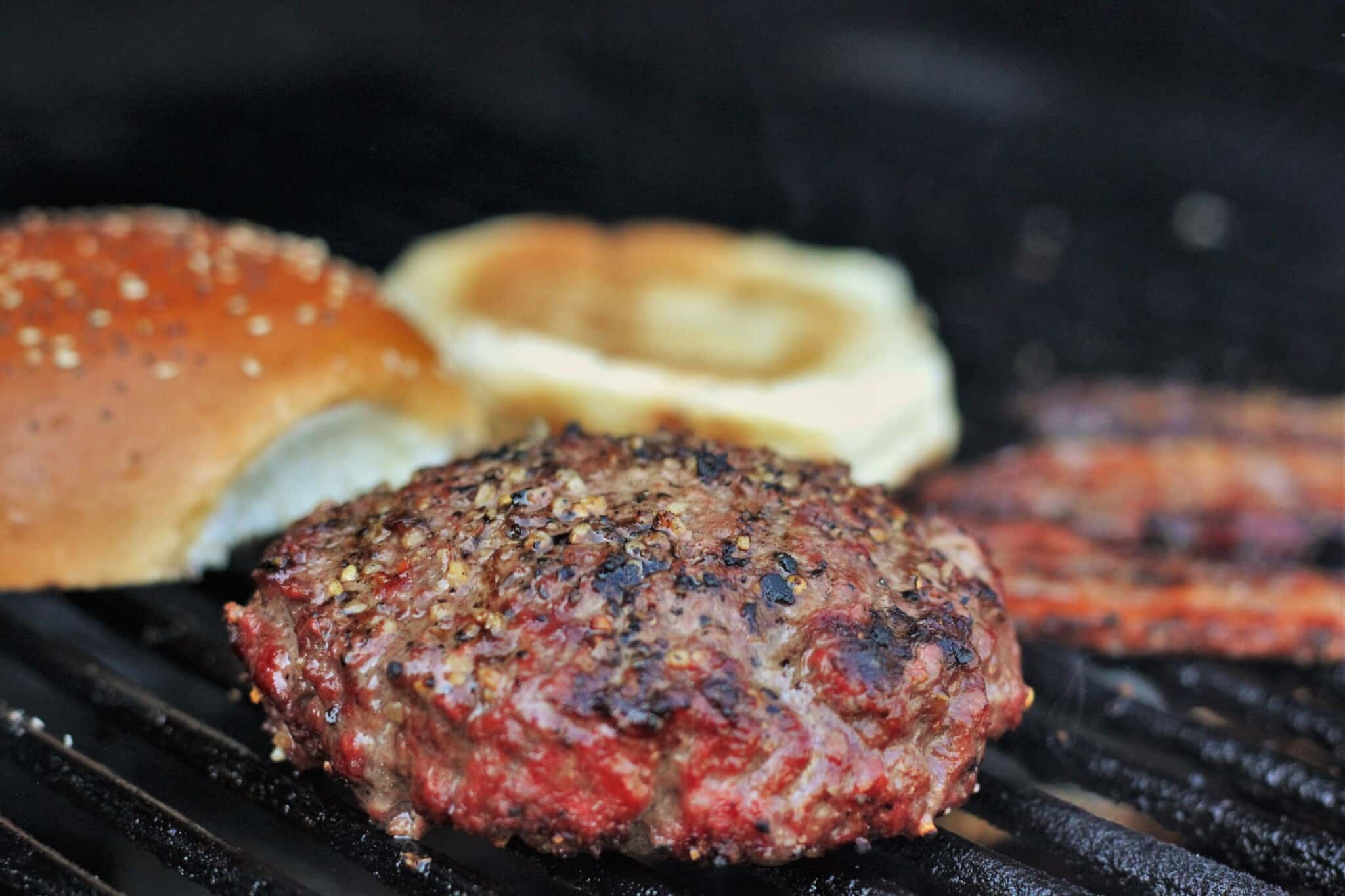 stuffed burger, buns, and bacon on the grill.