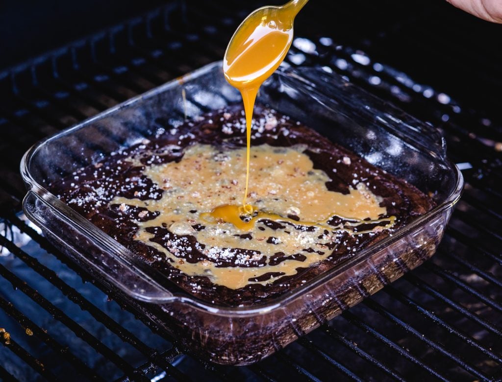 Caramel sauce being drizzled on top of brownies on the smoker.