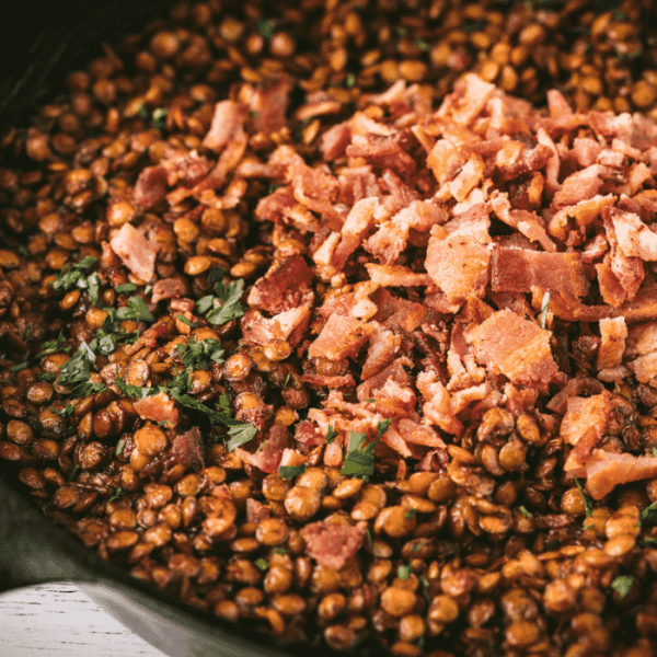 BBQ baked lentils in a cast iron skillet topped with bacon.