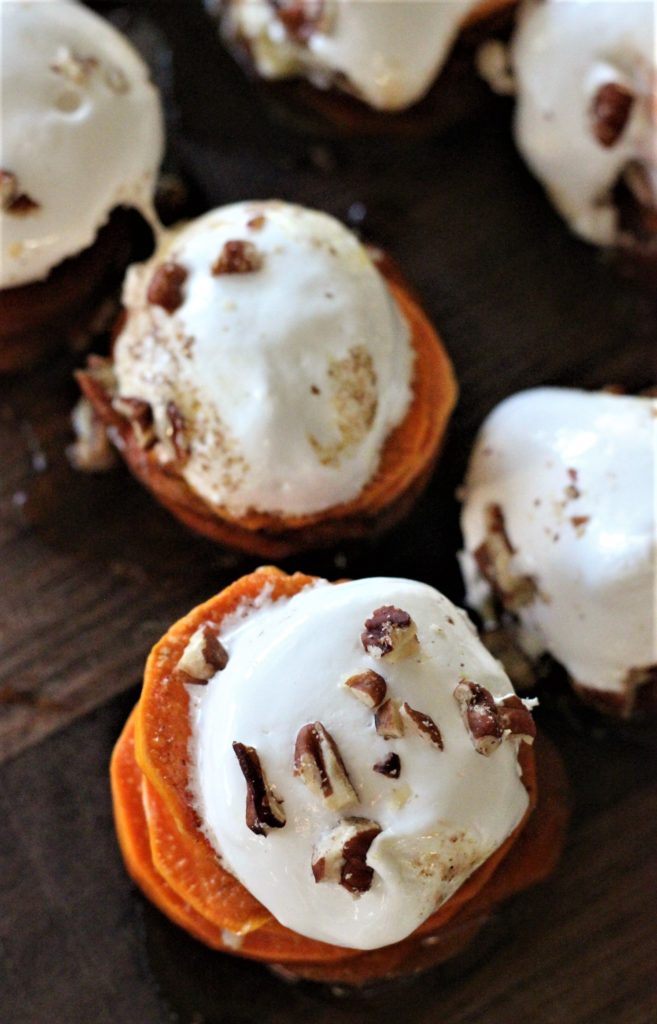 Overhead view of a half dozen candied sweet potato stacks topped with marshmallow fluff and pecans.