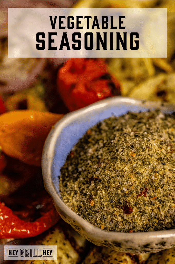Homemade vegetable seasoning in a bowl with grilled vegetables in the background with text overlay - Vegetable Seasoning