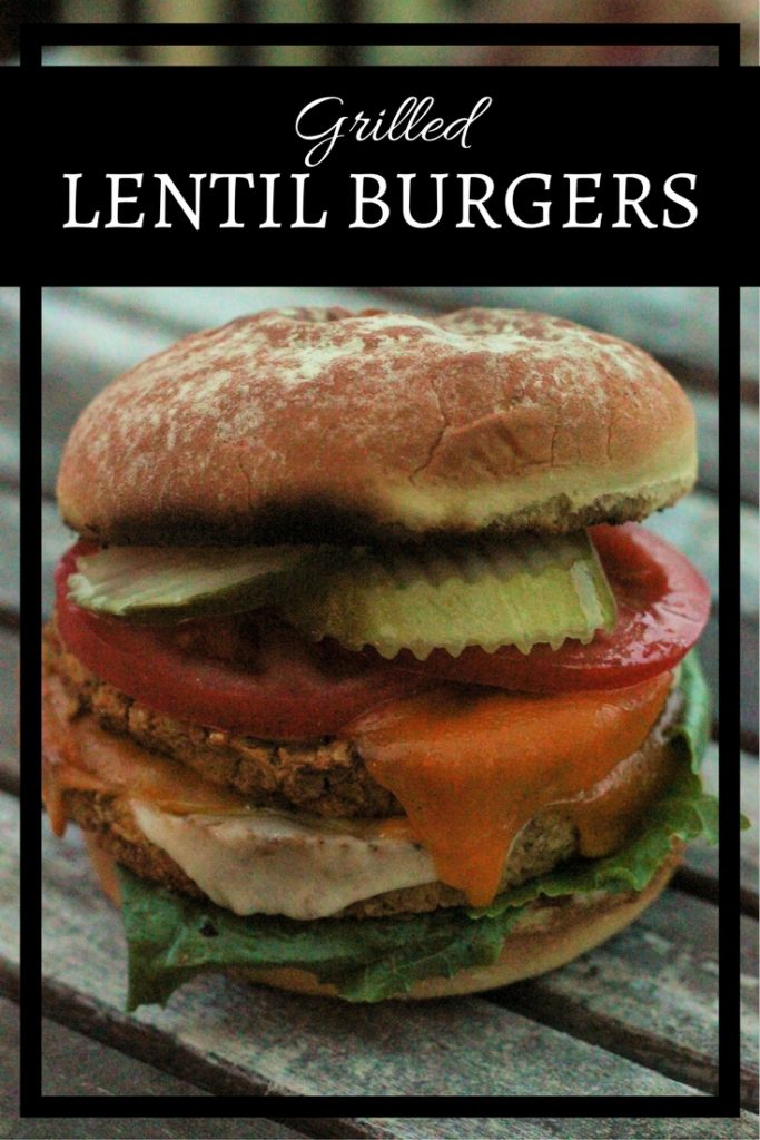 A Grilled Lentil Burger with lentil patty, lettuce, cheese tomatoes and pickles on a toaster hamburger bun.