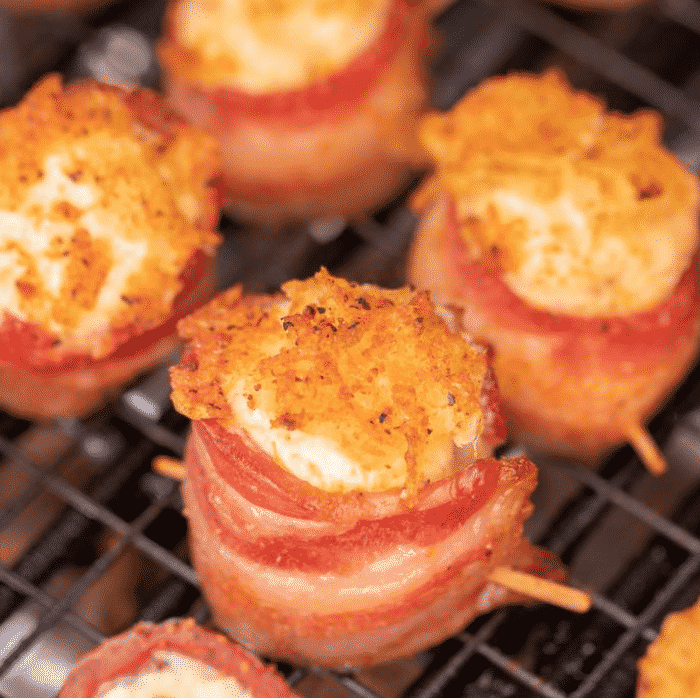 Pineapple cream cheese stuffed bacon wrapped pig shots on a cooling rack.