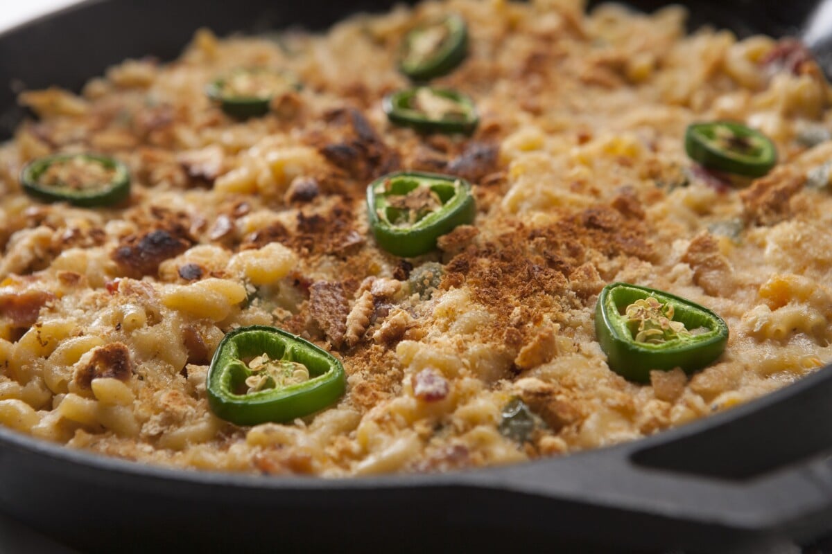 Smoked macaroni and cheese topped with toasted cracker crumbs and sliced jalapenos in a cast iron skillet.