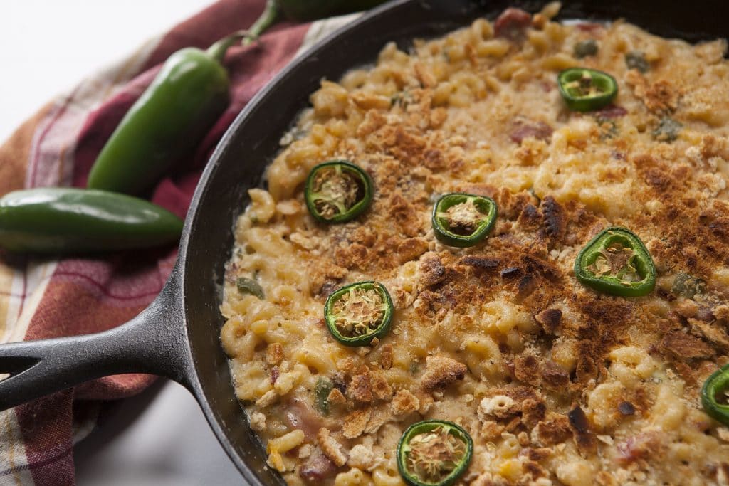 Macaroni and cheese topped with cracker crumbs and jalapeno slices in a cast iron skillet