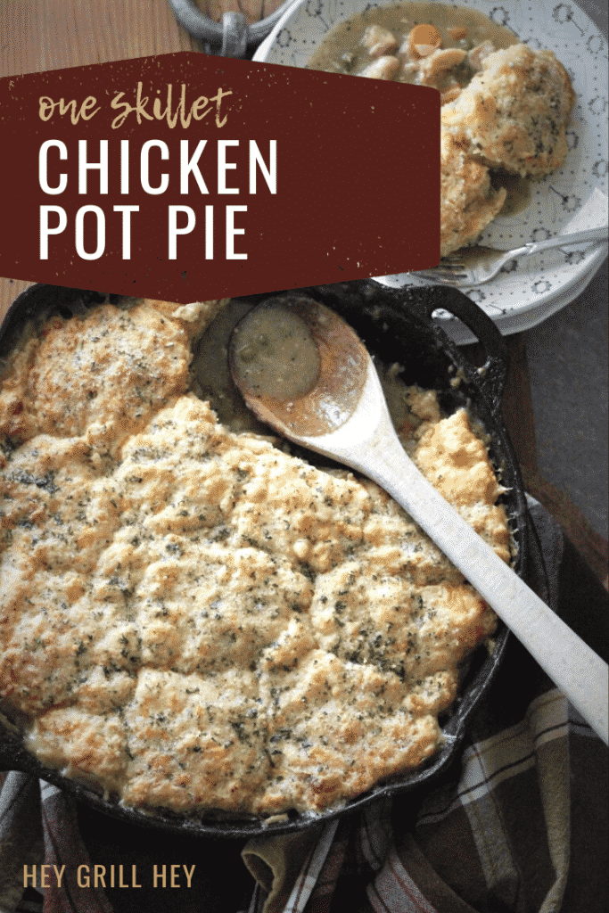Chicken pot pie with a cheddar biscuit crust in a cast iron skillet next to a bowl full of pot pie. Text overlay reads: "One Skillet Chicken Pot Pie."