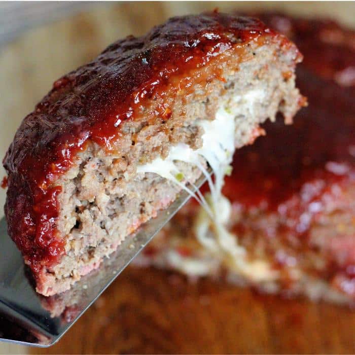 A slice of Jack'd up smoked meatloaf on a metal spatula with the remaining meatloaf in the background.