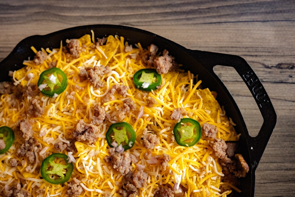 Shredded cheese, jalapenos, sliced jalapenos over eggs and tortilla chips in a casts iron skillet.