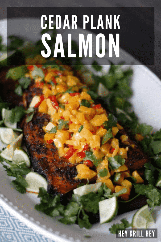 Cedar plank grilled salmon topped with mango salsa on a white oval plate.
