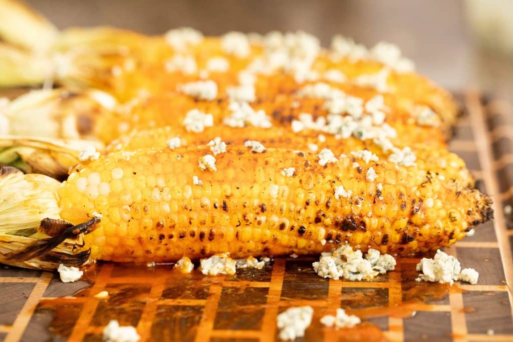 side shot of grilled corn with Buffalo sauce and crumbled blue cheese
