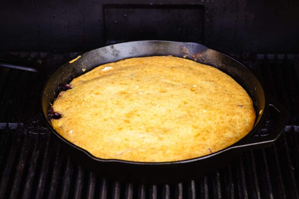 Dutch oven cobbler on the grill grates of a smoker.