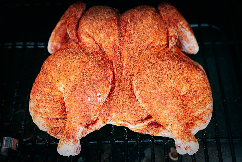 Spatchcock chicken on the grill grates of a smoker.