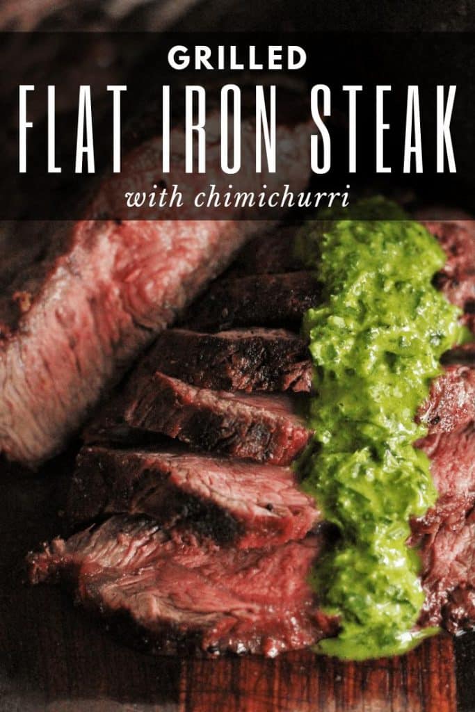 Slices of medium rare flat iron steak shingled on a wood serving board. Topped with a line of green chimichurri sauce.