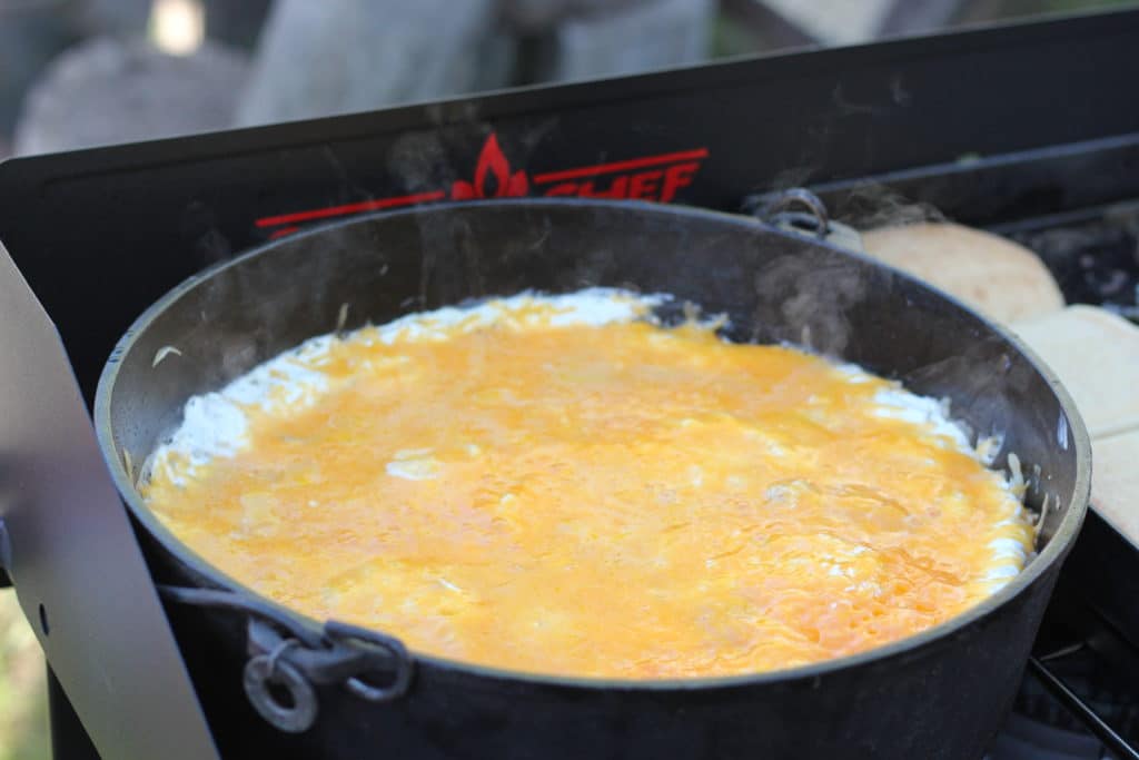 Cheesy Dutch Oven Potatoes on a camp stove.