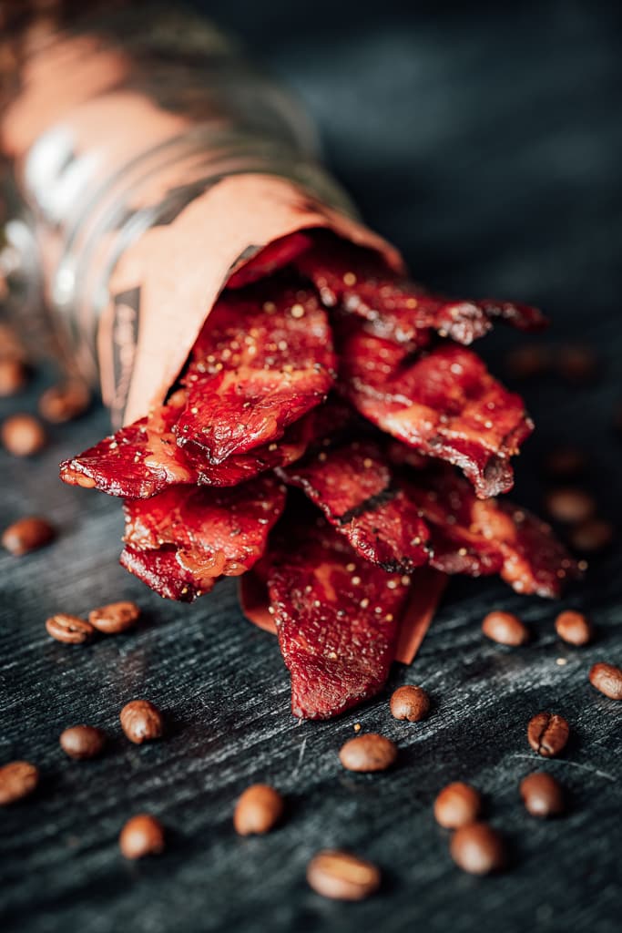 Sweet java beef jerky wrapped in Hey Grill Hey butcher paper surrounded by coffee beans.