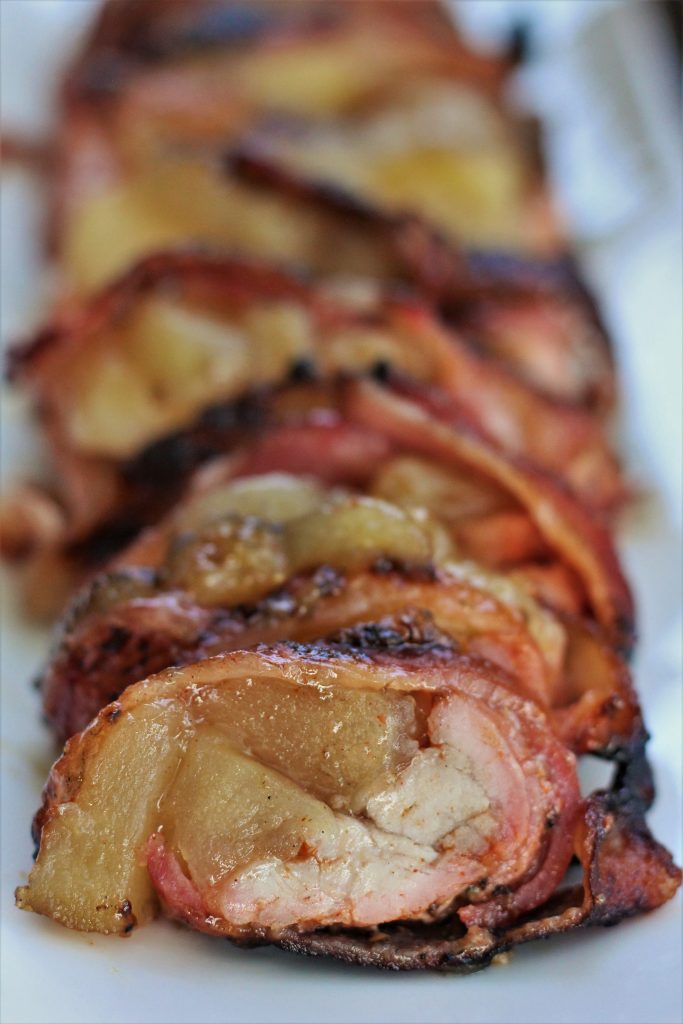 Grilled Bacon Wrapped Pork Tenderloin served on a white plate.
