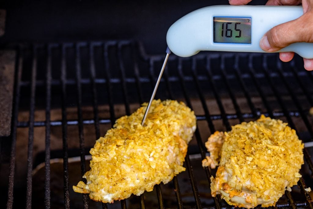 Potato chip crusted chicken on the grill reading a temperature of 165 degrees F.