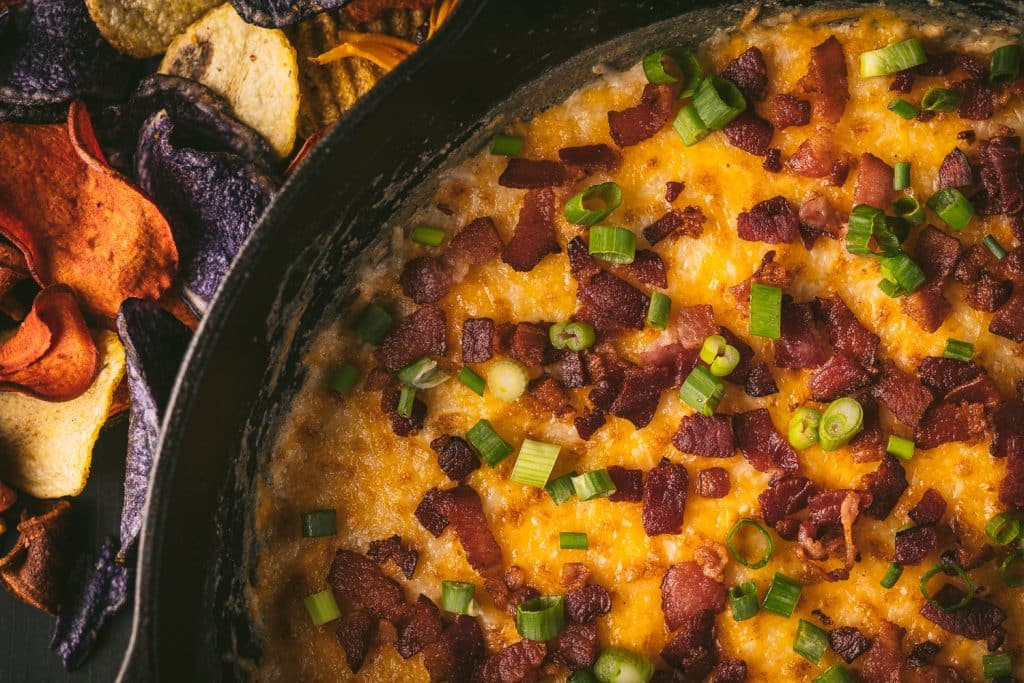 Smoked cheese dip in a cast iron skillet topped with bacon and green onions.