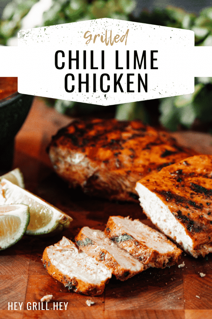 Sliced grilled chili lime chicken on a wooden cutting board with lime wedges and a whole grilled chicken breast in the background. Text overlay reads: Grilled Chili Lime Chicken.