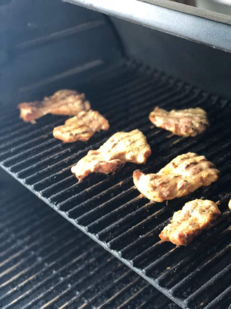 Chicken thighs being cooked on a grill.