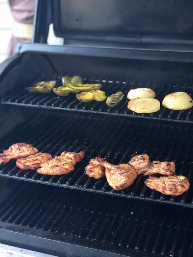 Chicken thighs on the grill with some jalapenos and onions.