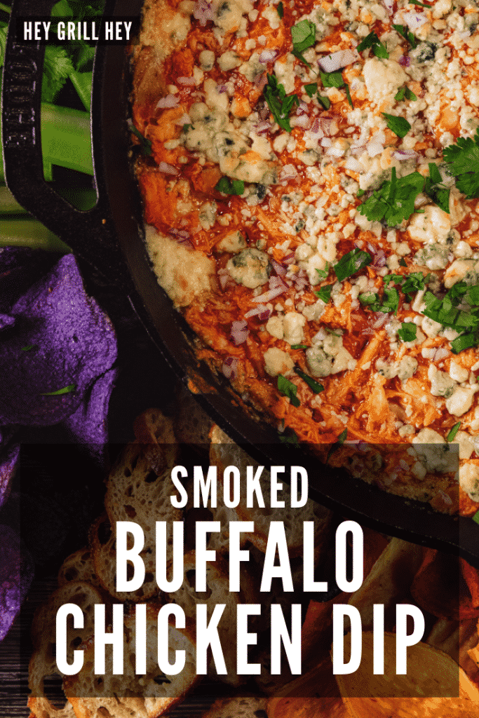 Buffalo chicken dip in a cast iron skillet surrounded by crostini and fresh veggies. Text overlay reads: Smoked Buffalo Chicken Dip.