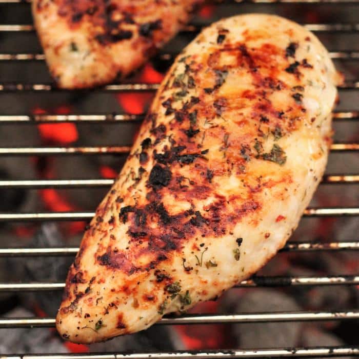 grilled chicken breasts on grill grates over hot coals