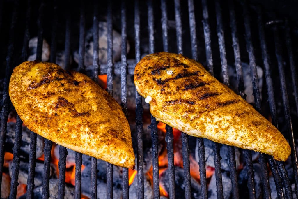 Two chicken breasts on grill grates.