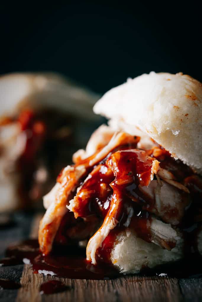 Smoked pulled chicken covered in whiskey peach BBQ sauce on a sandwich bun.