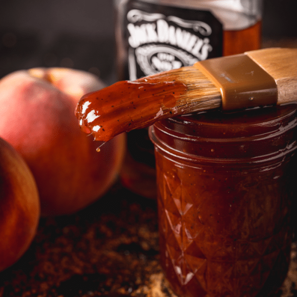 Whiskey peach BBQ sauce dripping off a sauce brush.