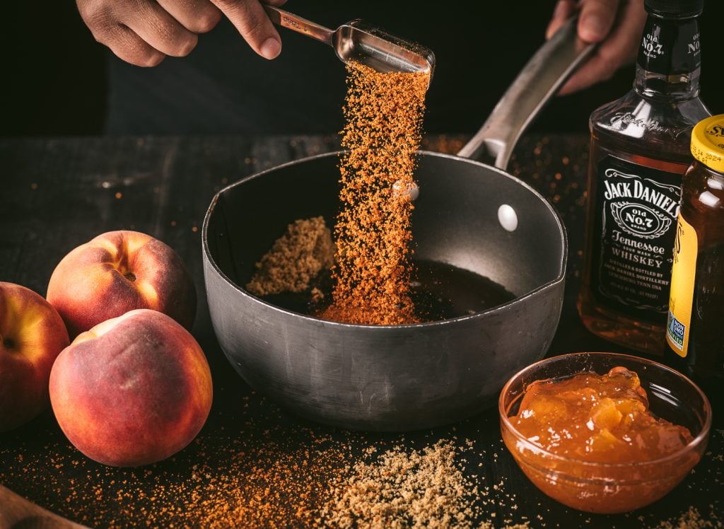 Brown sugar being poured into a saucepan.