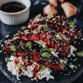 Smoked Asian style ribs garnished with sesame seeds over a bed of rice.
