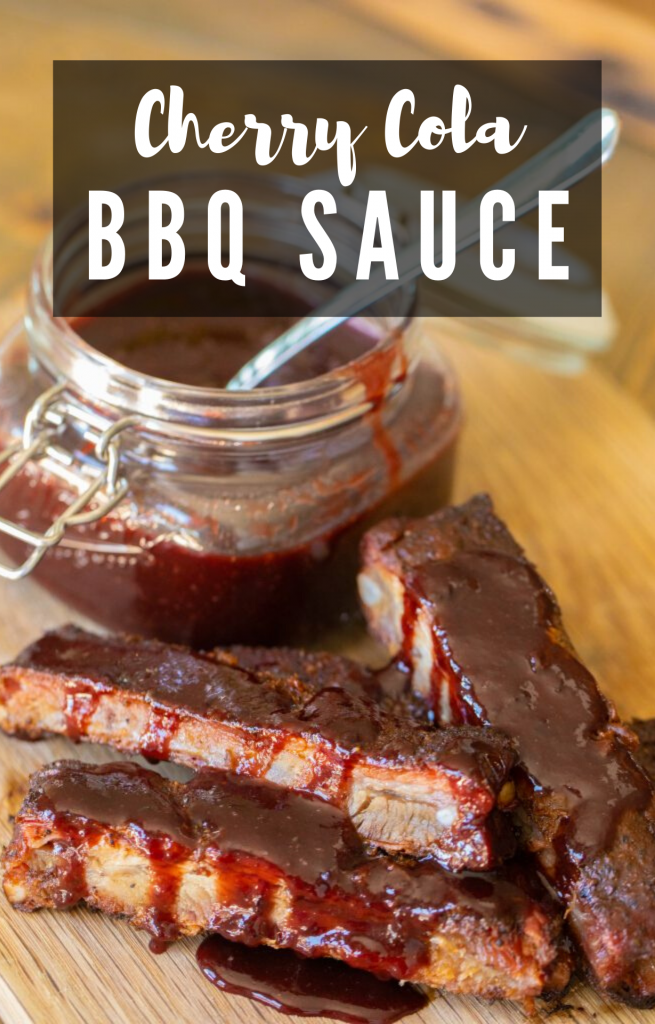 Pile of ribs drizzed in cherry cola BBQ sauce with a lidded mason jar full on cherry cola BBQ sauce in the background. Overlay text: "Cherry Cola BBQ Sauce."
