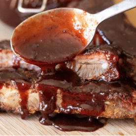 Cherry Cola BBQ Sauce being drizzled over pork ribs.