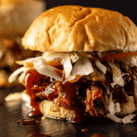 Cherry cola pulled pork sandwiches on a serving platter.